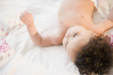 Mixed race baby laying on bed