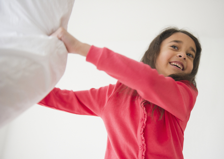 Mixed race girl holding pillowの写真素材