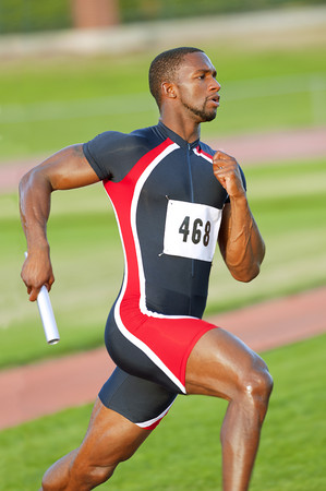 Black runner carrying baton in relay raceの写真素材