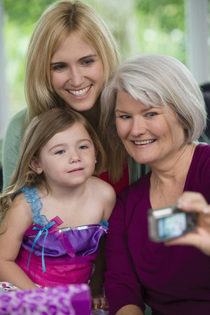 Smiling Caucasian grandmother, mother and daughter taking pictures