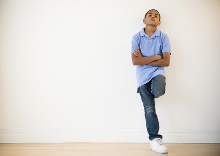 Frustrated Hispanic boy leaning against wall