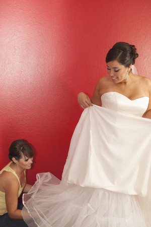 Hispanic bride putting on wedding dressの写真素材