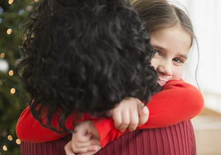 Mother and daughter hugging by Christmas treeの写真素材