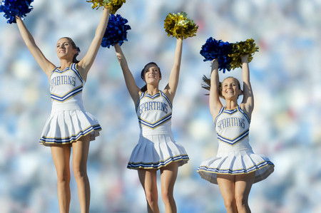 Caucasian cheerleaders on sidelines at football game