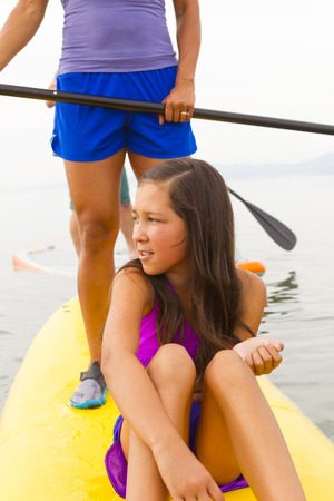 Mother and daughter riding paddle boardの写真素材