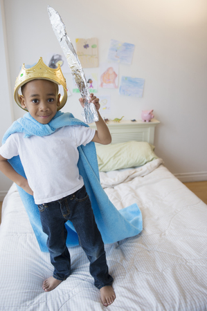African American boy wearing costume on bedの写真素材