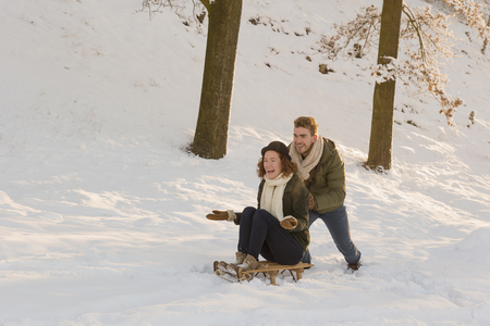 Caucasian man pushing girlfriend on sled in snowの写真素材
