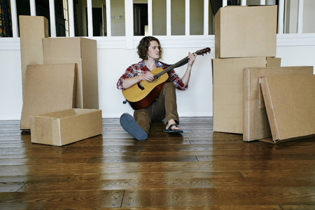 Caucasian man playing guitar in new home
