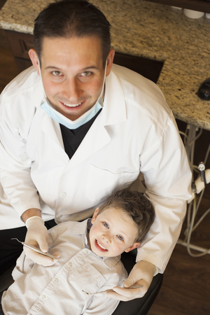 Caucasian dentist examining boy's teeth in officeの写真素材