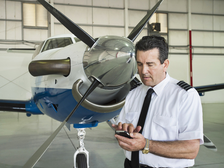 Caucasian pilot using cell phone in hangar