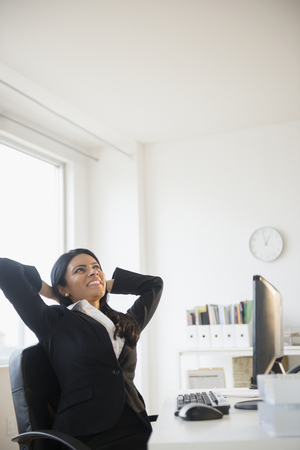 Indian businesswoman stretching at deskの写真素材