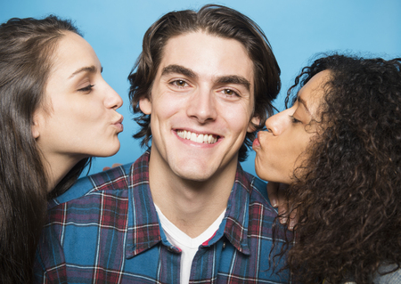 Girls kissing man's cheeksの写真素材