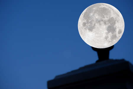 Moon on electric lamp on blue background.の写真素材