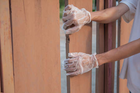 Wearing gloves opening wooden fence.