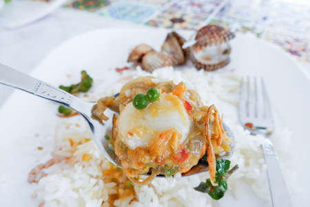 Stir fried scallop with spicy sauce and herbs in spoon.の写真素材