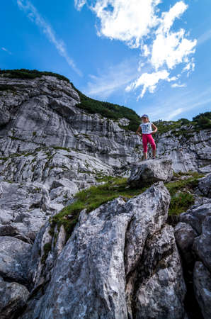 German Alps. August 2017: Young girl standing with on top of the rock and looking into a wide valley.のeditorial素材