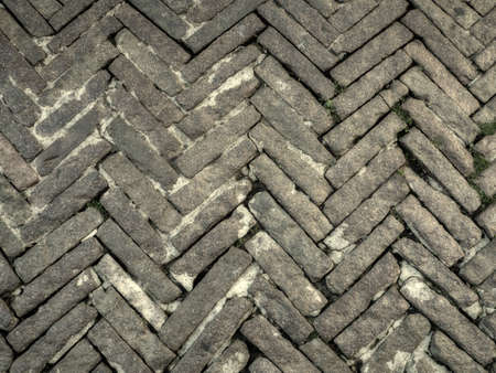 Old medieval pavement. Gray stone blocks laid out in a herringbone fashionの写真素材