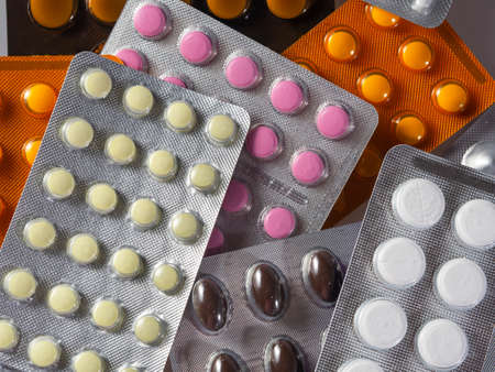 Blisters with medicines. Tablets of different shapes and different colors in blisters fill the...