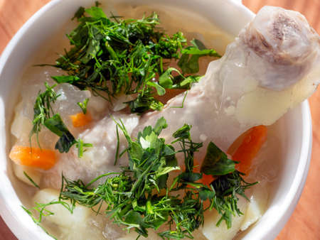 Chicken soup with vegetables and herbs close-up. In a bowl with soup is chicken drumstick. Hot meal for lunch.の写真素材