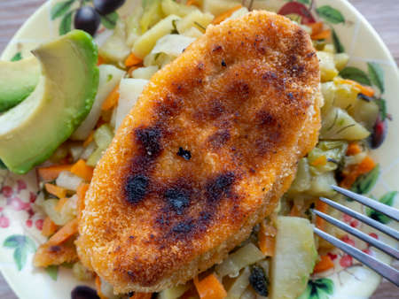 The second dish with a cutlet and vegetables close-up. Home background with food.