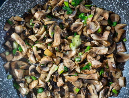 Cooking mushrooms. Sliced mushrooms and green onions in a pan close-up. Gourmet food background.の写真素材