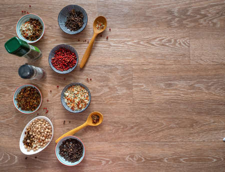 Spices, seasonings, chickpeas in plates and banks on a wooden table. Space for text. Background with spices and seasonings.の写真素材
