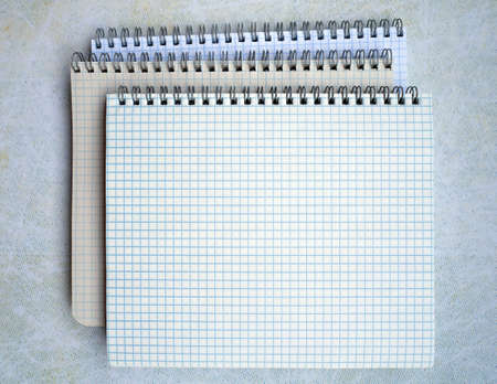 Three spiral binding notebooks are stacked. They are open. You can write text on a blank sheet.