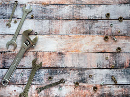 Wrenches and fasteners are located around the wooden background. Empty space for text. Background...