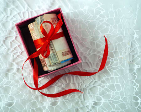 Rolled up Russian money tied with a ribbon on a bow. The money is in the box. The box stands on...