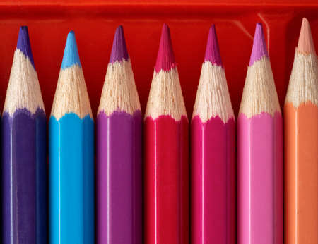 A set of new colored pencils is arranged in a row in the box. Close-up. Background with colored...