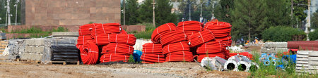 Flexible corrugated pipes for cable laying are rolled up. Metal supports, pipes, curbstone and other building materials lie on the ground. Background with building materials for industry and business.の写真素材