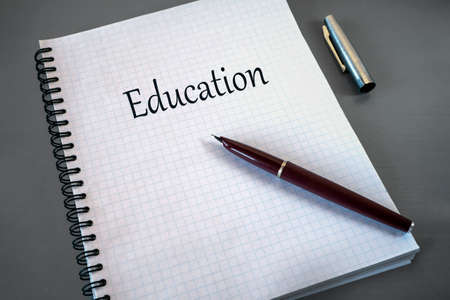 An open notebook is on the gray surface. The word "Education" is written on a blank sheet of notebook. There is a fountain pen on the notebook. Learning, education concept.の写真素材