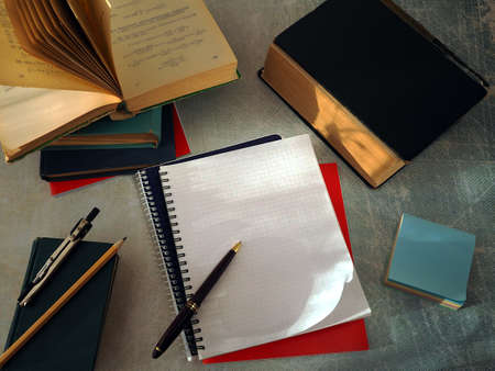 Open books and notebooks lie on the table. There is a pen on a clean notebook page. The concept of education, study, scientific work.の写真素材