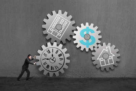 Businessman rolling a large concrete gear connect with others  each with clock, office, home and money drawing in concrete wall background の写真素材