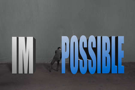 Businessman push word "impossible" possible to separate, to make it possible in concrete wall background.の写真素材