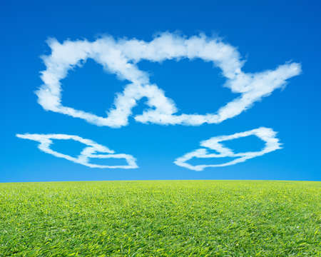 Recycling symbol shape cloud in blue sky with green fresh meadowの写真素材