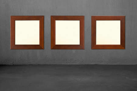 Three blank wooden frames on concrete wall, nobody