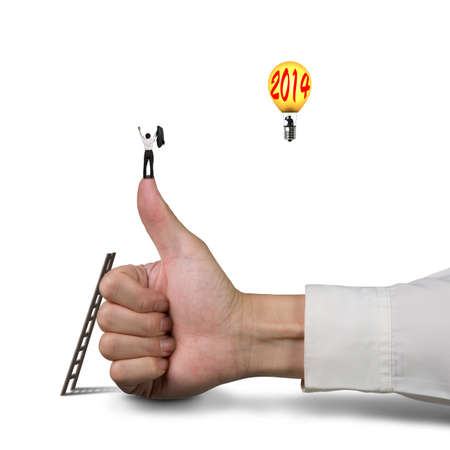 Businessman standing on top of thumb, another in balloon with 2014, white backgroundの写真素材