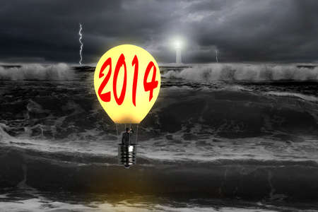 Man taking glowing lamp balloon with dramatic ocean, lightning and lighthouse の写真素材
