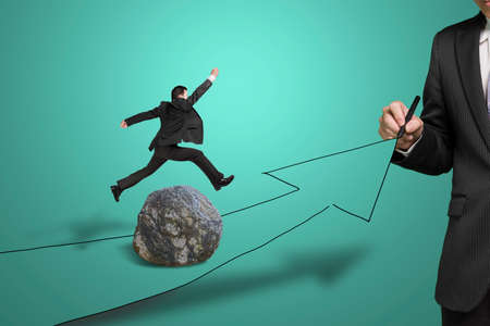 Businessman drawing road with growing arrow, another jumping over large rock on the wayの写真素材