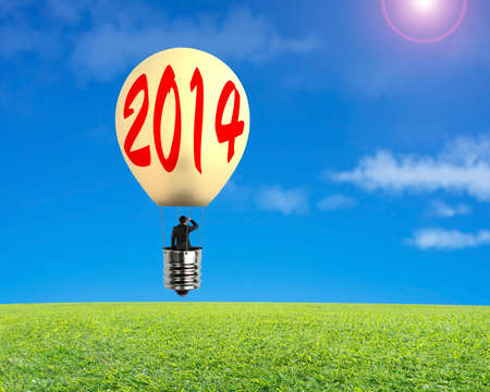 Man taking glowing lamp balloon floating over green meadow and looking at distant placeの写真素材