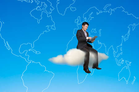 Businessman using tablet and sitting on cloud with global map in sky backgroundの写真素材