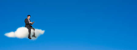 Businessman using tablet and sitting on cloud in sky background,, bannerの写真素材