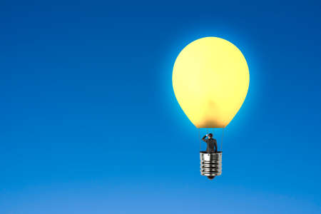 Man taking glowing lamp balloon looking at distant place with blue sky backgroundの写真素材
