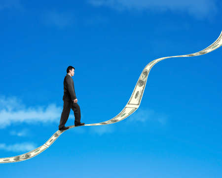 Businessman walking on growing money trend with cloud and blue skyの写真素材