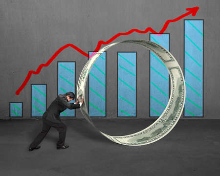 Businessman pushing money circle with growing red arrow and chartの写真素材
