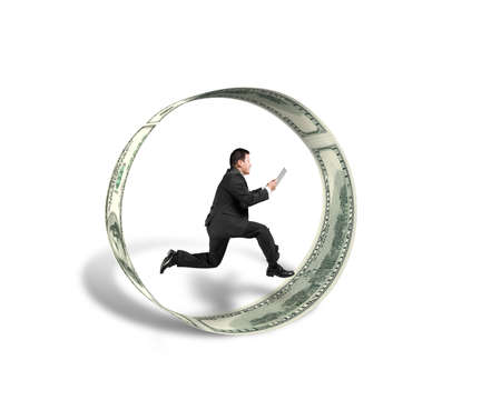 Businessman using tablet running inside money circle in whiteの写真素材