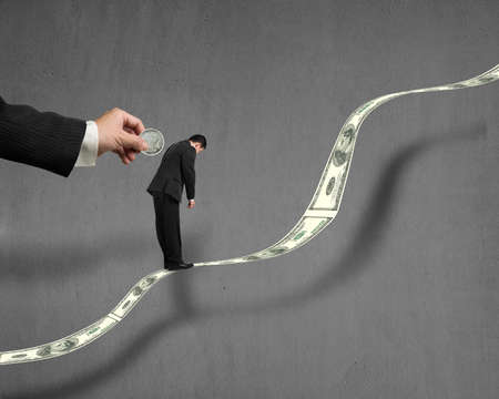 Hand insert coin into businessman back hole which standing on growing money trend with concrete wallの写真素材