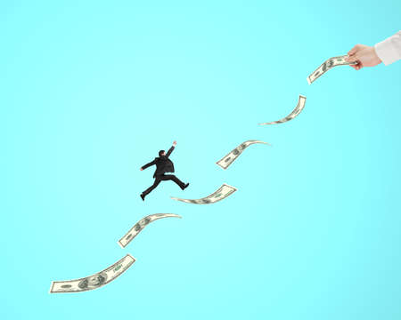 Businessman jumping on money with another man hold one, in green backgroundの写真素材