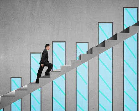 Businessman climbing on concrete stair with chart on concrete wall